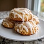 Stapel von Soft Sweet Italian Almond Ricotta Cookies, bedeckt mit dickem, wei&szlig;em Zuckerguss und Mandelst&uuml;cken.