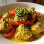 Nahaufnahme von cremigem Coconut Curry Chicken mit leuchtend roten Paprikastreifen und frischer Petersilie.
