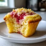 Nahaufnahme eines angeschnittenen Lemon Strawberry Swirl Cupcakes mit saftiger F&uuml;llung und knusprigen Streuseln.