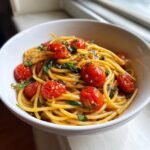 Eine wei&szlig;e Sch&uuml;ssel gef&uuml;llt mit cremigem Tomato Basil Pasta, garniert mit gl&auml;nzenden, ger&ouml;steten Kirschtomaten und frischem Basilikum.